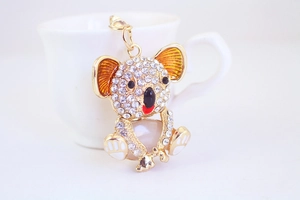 Close-up of a koala keychain with golden metal, white stones and orange enamel