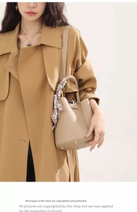 Detail of beige lychee leather bucket bag with silk scarf and metal feet on the bottom