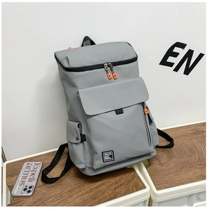 Detail view of a gray travel backpack featuring orange zipper pulls and Spunk logo label