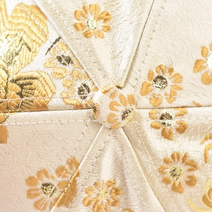Detail of floral embroidery on beige brocade baseball cap with golden silk threads