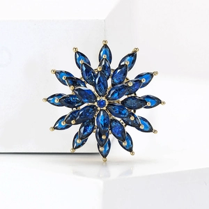 Detailed macro shot of rotating snowflake brooch with blue marquise stones and gold plating