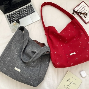 Dettaglio di borse tote in lana con stelle argentate nei colori grigio e rosso sul letto