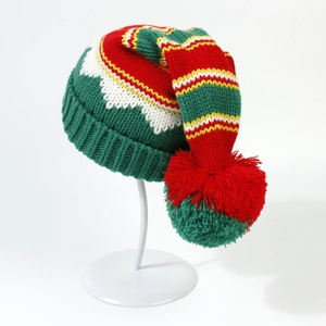 Close-up of colorful striped knitted Christmas hat with large red and green pompom detail