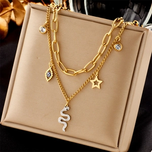 Double-layered gold stainless steel necklace with snake, star, and evil eye charms on a pad