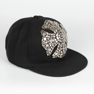 Detail of Harajuku style flat brim cap with intricate metal cross and stud embellishments