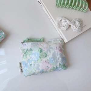 Gros plan d'une mini pochette en coton à fleurs avec fermeture éclair verte