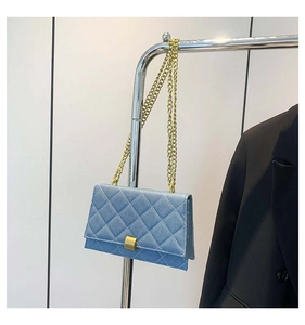 Detail of light blue denim crossbody bag featuring quilted patterns and gold metal chain