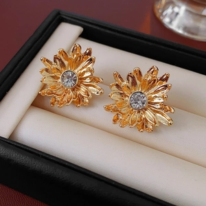 Close-up of golden sunflower stud earrings with sparkling crystals in a black jewelry box