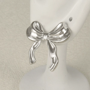 Macro detail of silver bow-shaped 304 stainless steel earrings on a display