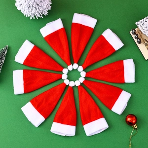 Detailed view of ten mini red plush Christmas hats arranged in a circle on green background