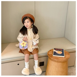 Girl in beige fringe cardigan and brown beret holding a purple flower crossbody bag