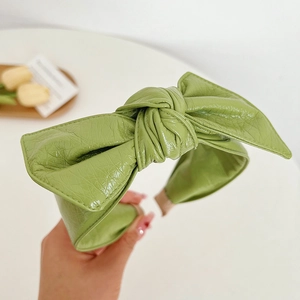 Detailed view of large green faux leather bow headband with premium wrinkled texture