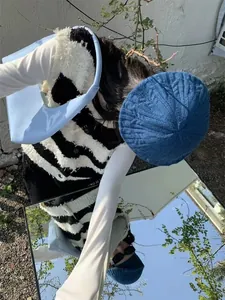 Creative mirror shot of blue patent leather crescent bag with knitted beret and striped vest