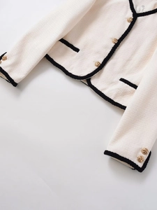 Détails de la veste en tweed crème avec bordures noires et boutons dorés en relief