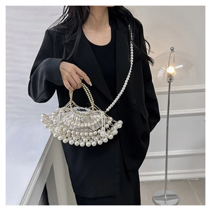 Detail of beaded pearl evening bag with metal frame and chain strap on a black blazer