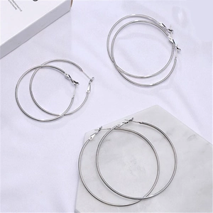 Detailed view of three pairs of silver hoop earrings in varying sizes on marble background