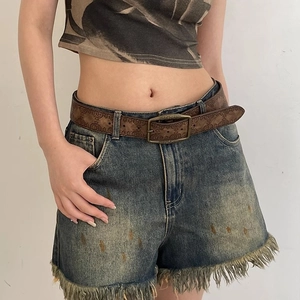 Vintage embossed brown leather belt styled with denim shorts and a printed crop top