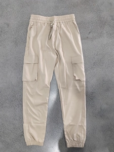 Detail of beige cargo pants showing elastic drawstring waist and large flap pockets