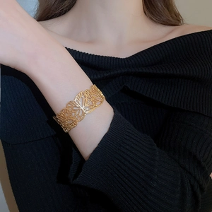 Detail of gold hollow butterfly cuff bracelet showcasing intricate floral cutout metalwork