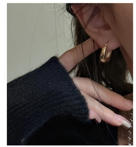 Close-up of minimalist gold U-shaped hoop earring on model showing sleek metallic finish