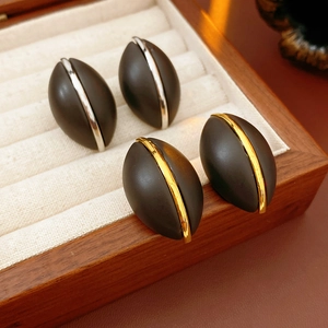 Dettaglio di orecchini ovali in legno con strisce oro e argento in portagioie