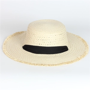 Detail of beige straw sun hat featuring fringed edges and wide black fabric ribbon trim