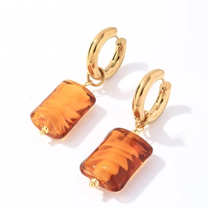 Detail view of amber natural stone pendants on gold stainless steel hoop earrings