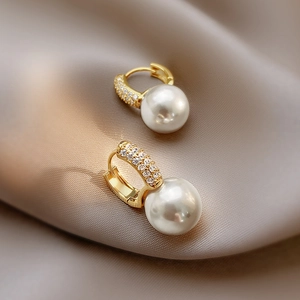 Elegant 18K gold-plated pearl hoop earrings with shimmering pave-set crystals on silk fabric