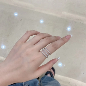 Macro detail of multi-layer silver heart ring with sparkling zircons on a finger