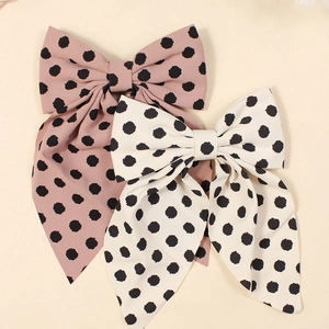 Close-up of pink and white fabric bow hair clips with classic black polka dot patterns