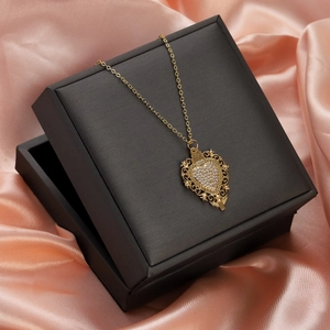 Detailed view of vintage gold heart pendant with red ruby and zircons on silk
