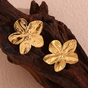 Detail showing the brushed metal texture and floral petals of the golden flower earrings