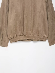 Detail of the elastic hem on this brown faux suede jacket showing fine stitching quality