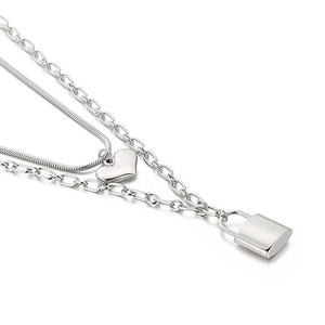 Double-layer silver stainless steel necklace with heart and padlock pendants on white background