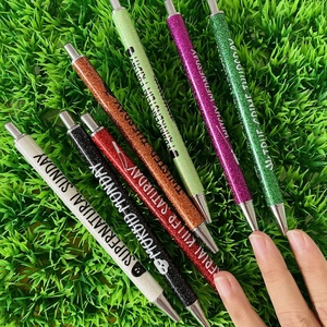 Set of seven glitter pens for Halloween and Christmas on green artificial turf