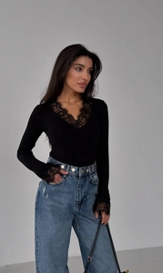 Close-up of elegant black slim fit top featuring intricate lace V-neck and cuffs detail