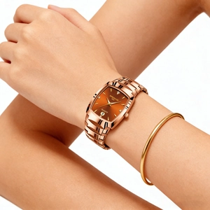 Detailed view of women's rose gold square watch with orange dial and diamond markers