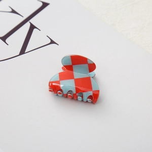 Macro shot of small checkered hair claw clip in red and light blue with a glossy finish