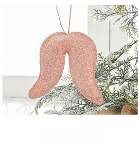 Pink glitter wing ornament with hanging string on snow-covered Christmas branches
