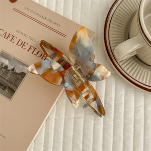 Close-up of butterfly acetate hair claw in blue and orange on French cafe-style background