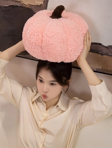 Detail of pink pumpkin plush pillow showing soft sherpa wool texture and brown stem