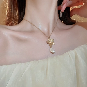 Close-up of elegant gold flower necklace with pearl pendant on model neck