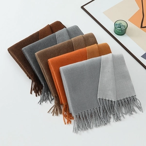 Flat lay of multiple colorful tasseled scarves in brown, grey, camel and orange tones