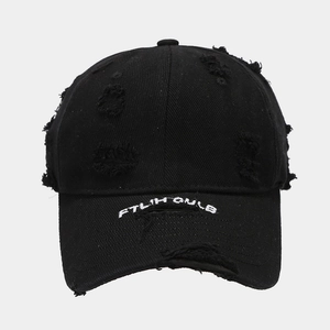Detail of distressed black baseball cap with torn fabric and white letter embroidery