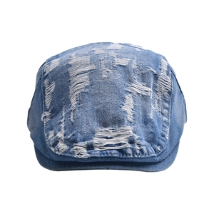 Detail of distressed blue denim newsboy cap showing frayed edges and vintage textures