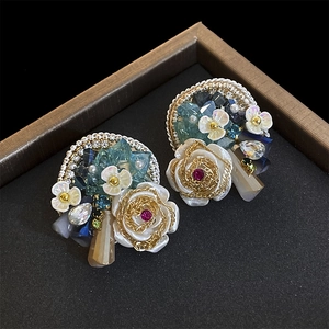 Detailed shot of pearl and crystal flower earrings in a premium brown display box