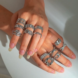 Detailed view of silver stainless steel rings with geometric leaf patterns worn on hands