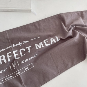 Dettaglio di runner da tavola in lino marrone con scritte bianche Perfect Meal stampate