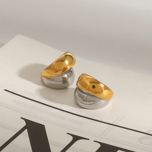 Macro detail of wave-shaped two-tone gold and silver ear clips with a polished mirror finish