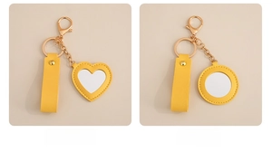 Detail of yellow PU leather heart and round mirrors with golden keychain and fine stitching